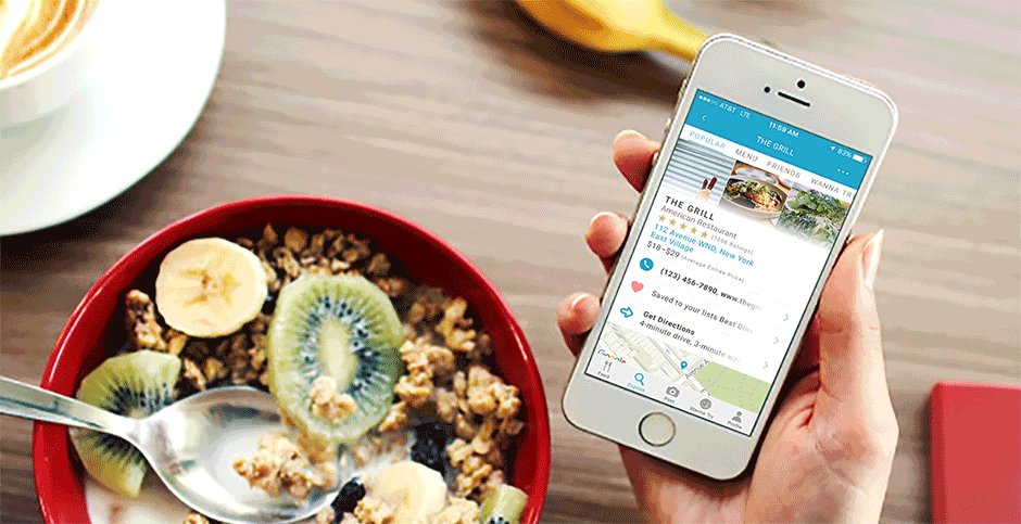 Wine 'n Dine restaurant discovery app shown on an iPhone in someone's hand held over a bowl of fruit and granola on a table. The person is looking up information about a restaurant.